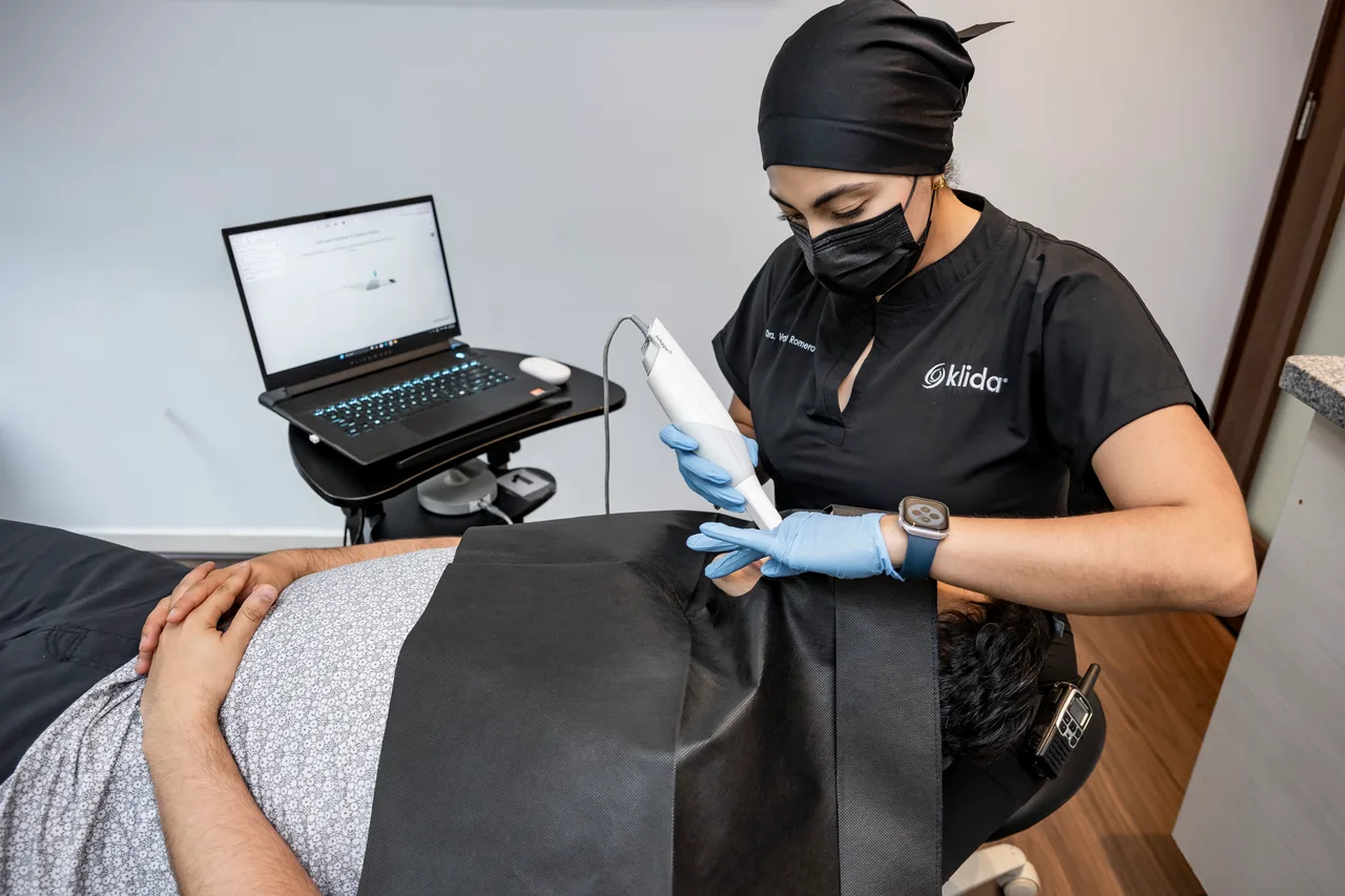 Escaneo intraoral a un paciente en el sillón, con la laptop a la vista