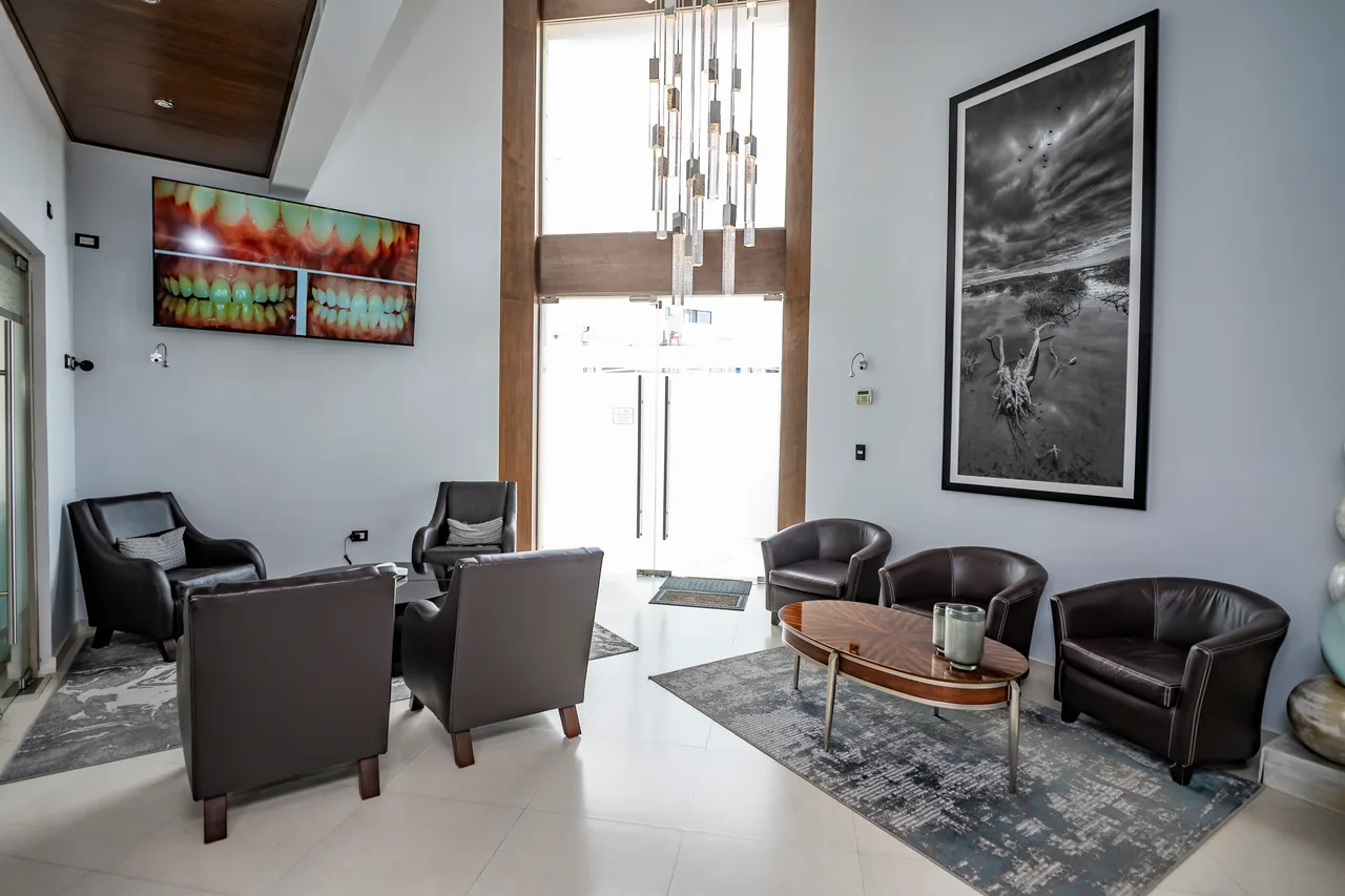 Sala de espera de doble altura con sillones y mesa de centro